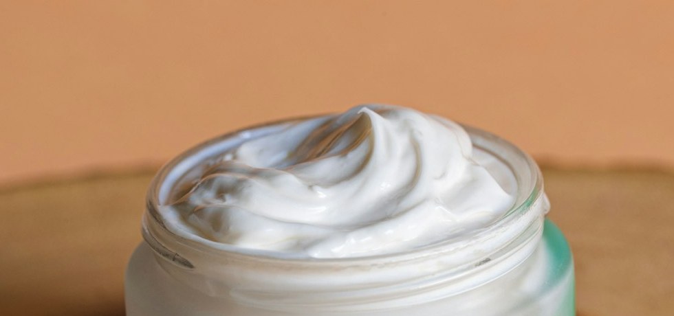 Geöffneter Cremetiegel mit weißer Textur in Nahaufnahme