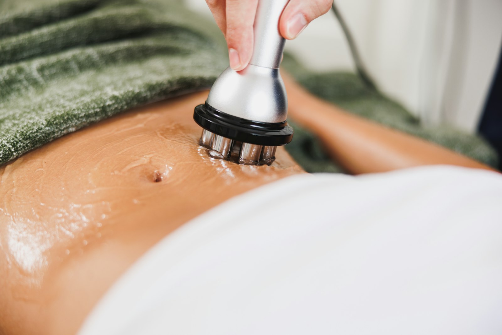 Apparative Körperbehandlung mit Handstück und Gel am Bauch